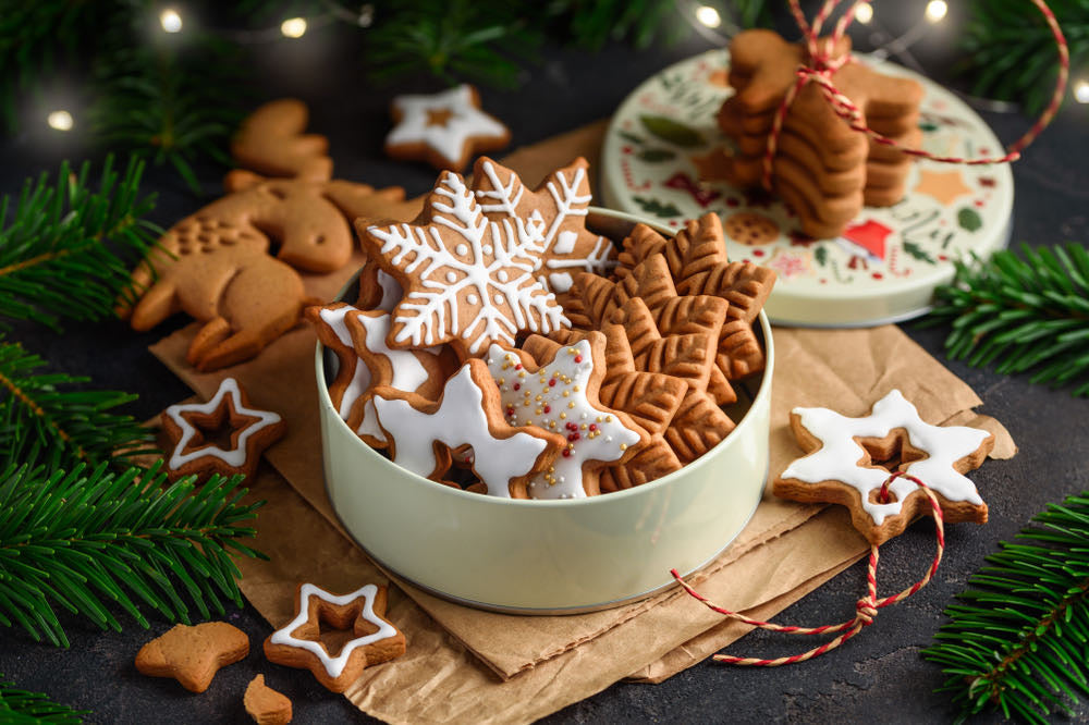 Biscuits de Noël en forme d'étoiles et de sapins glacés, présentés avec des branches de sapin