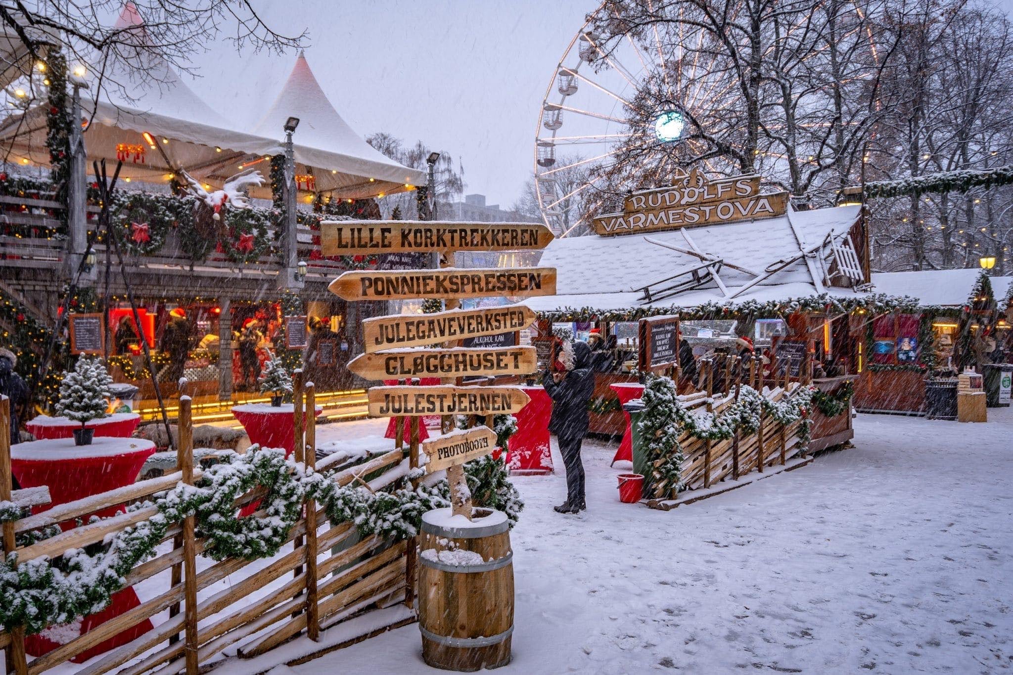 Marché de Noël enneigé avec stands en bois et illuminations féeriques